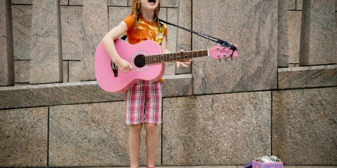 girl playing guitar near wall